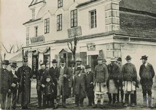 Jews and other people in front of the shops.  Above the entrance to the left is a Jewish name - M.Klienfeld